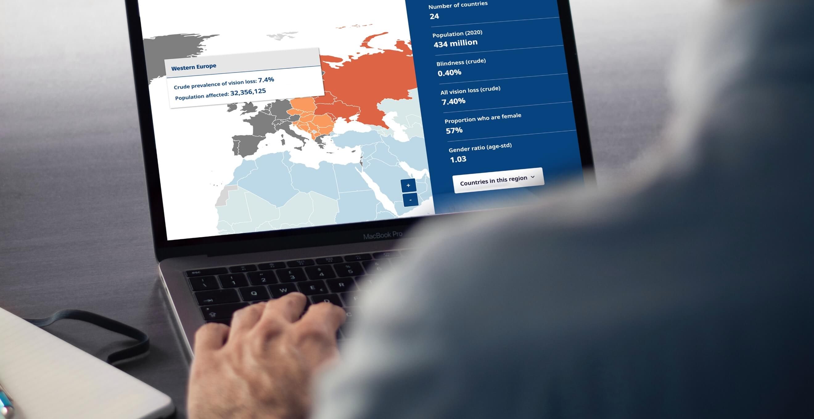 A person sat down with a laptop navigating through the IAPB Vision Atlas website